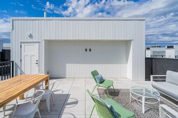 a patio with green chairs and a wooden table and a white building at Matilda 235 Townhomes, Des Moines, 50309